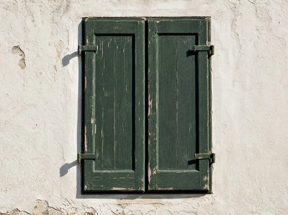 Verwitterte Fensterläden an einer weißgetünchten Wand